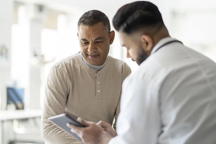 Physician consulting with a patient and using a tablet to explain health information during a checkup